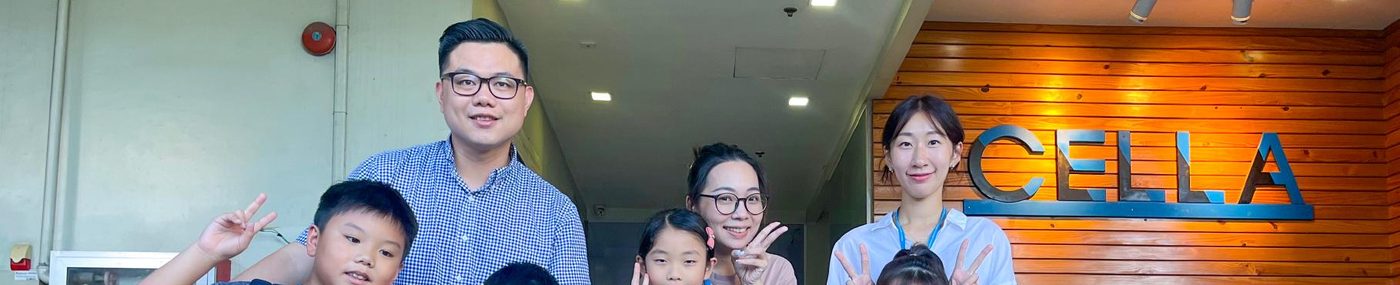 셀라 로고 벽 앞에서 손가락 브이를 한 보호자와 아이들