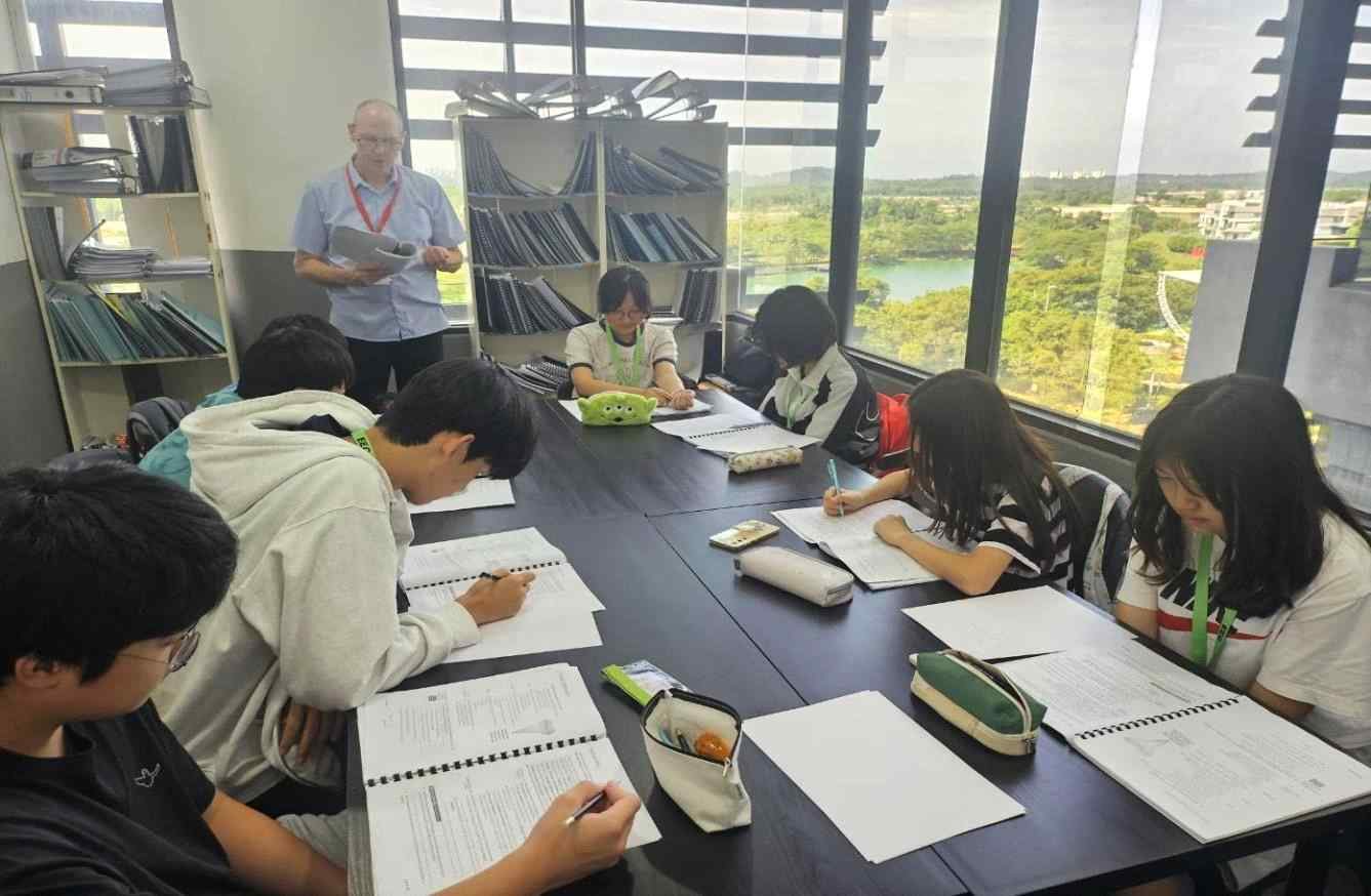EEC 어학원 창가 교실에서 선생님과 함께 교재를 펴고 그룹 수업을 듣는 학생들