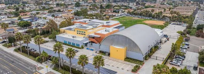 San Diego Academy 캠퍼스 항공 사진: 아치형 지붕 건물과 운동장, 주변 주택가